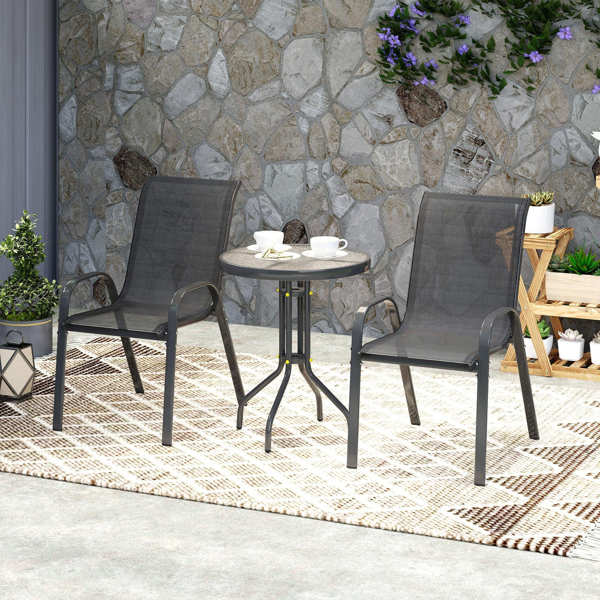 Two dark mesh stackable chairs with round metal bistro table for outdoor seating