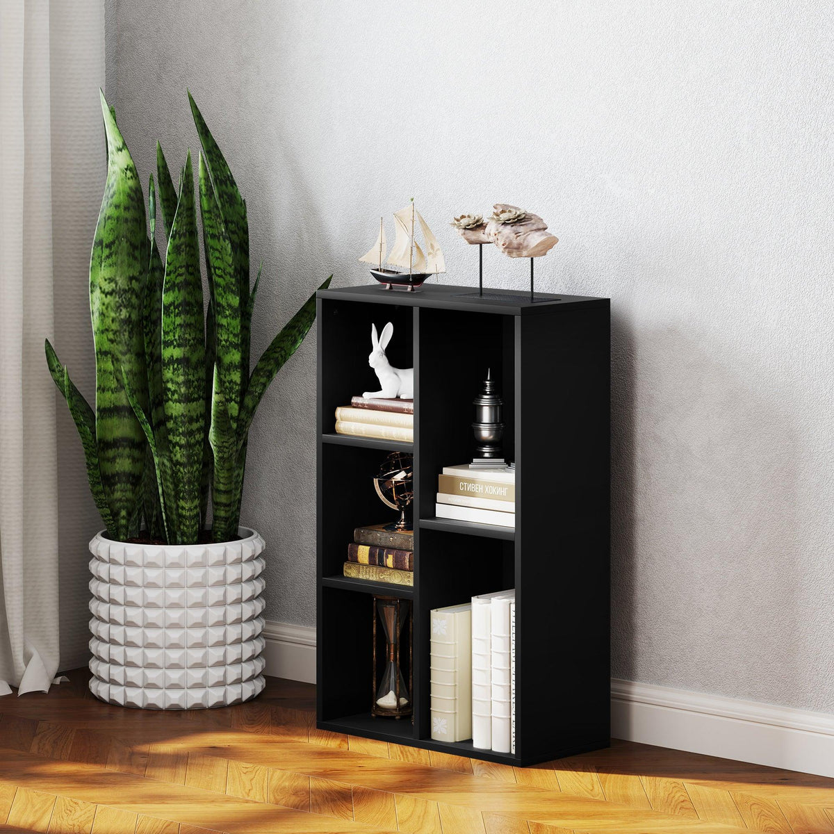 Black bookshelf with five open cubes, plant pot and decorative items on shelves