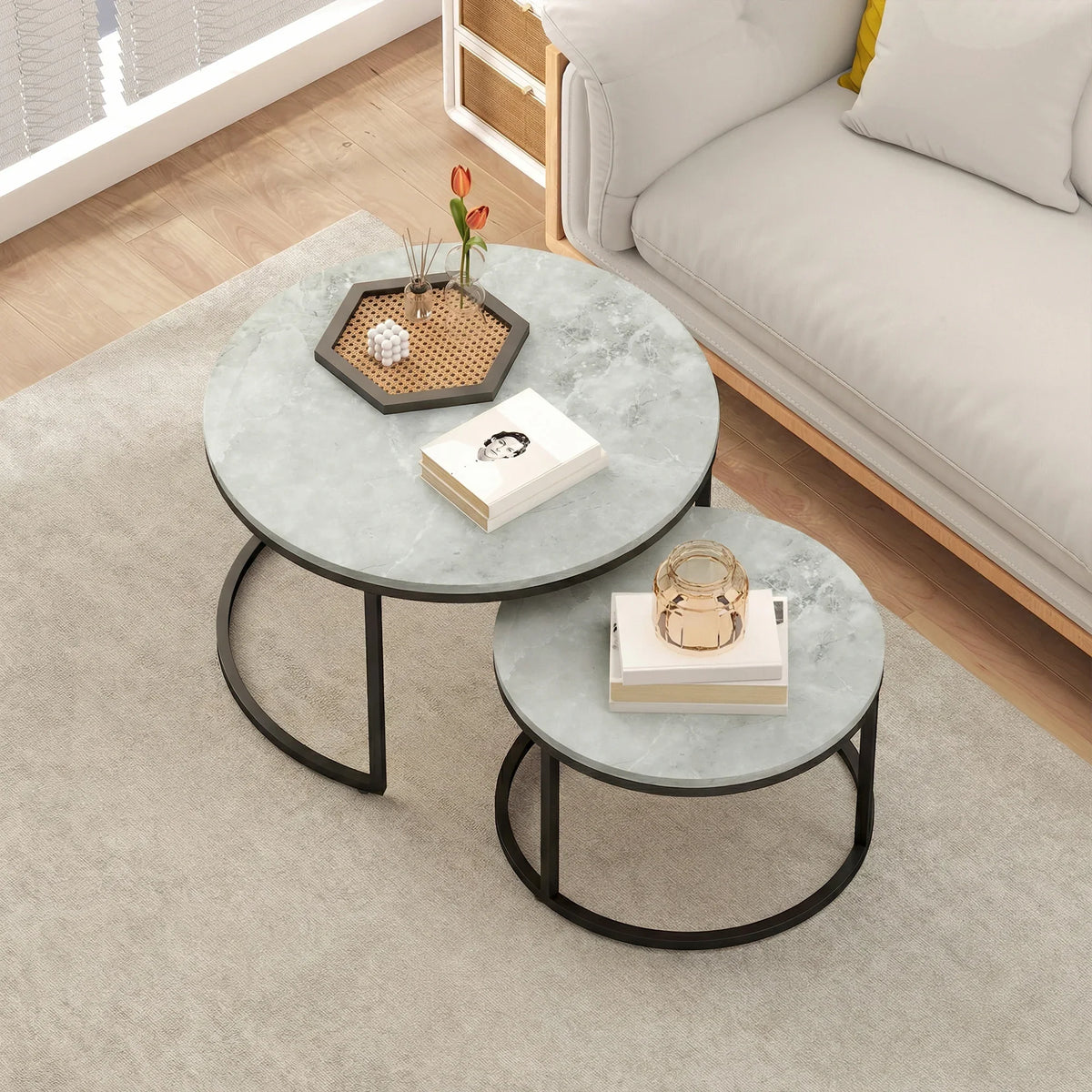 Grey marble-effect round nesting tables with black frames and storage items on top