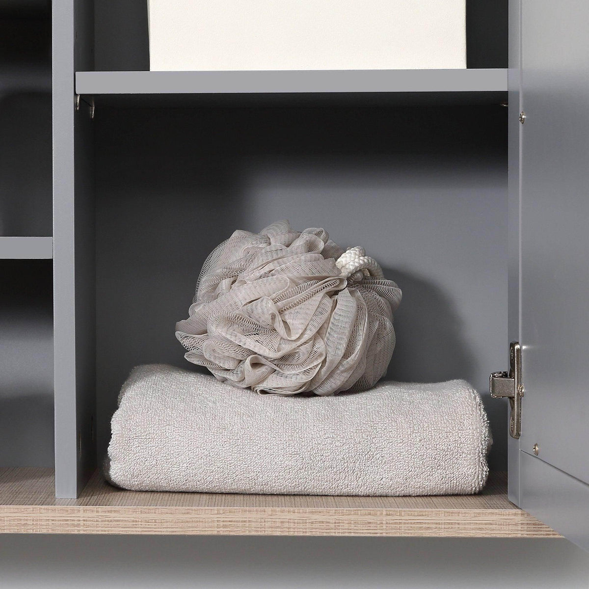 Grey bathroom wall mirror cabinet open, showing folded towel on lower shelf