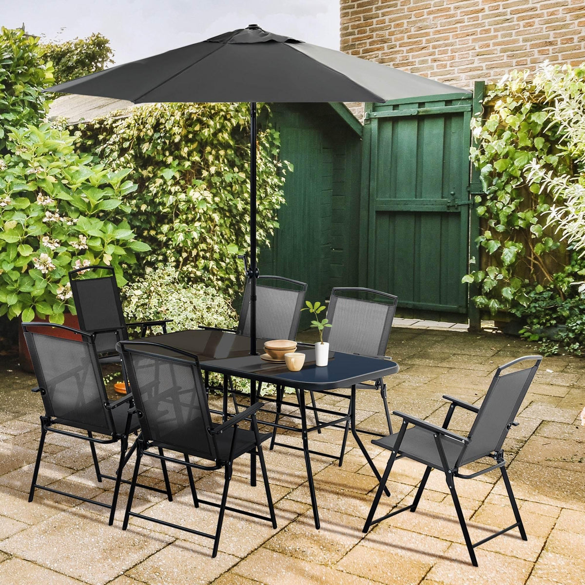 Outdoor dining set with black metal table, tempered glass top, and 6 folding chairs