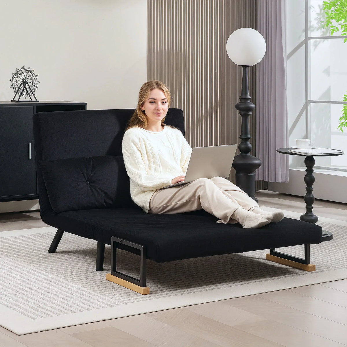 Black sofa bed with tufted back cushions, wooden armrests, and sturdy dark legs