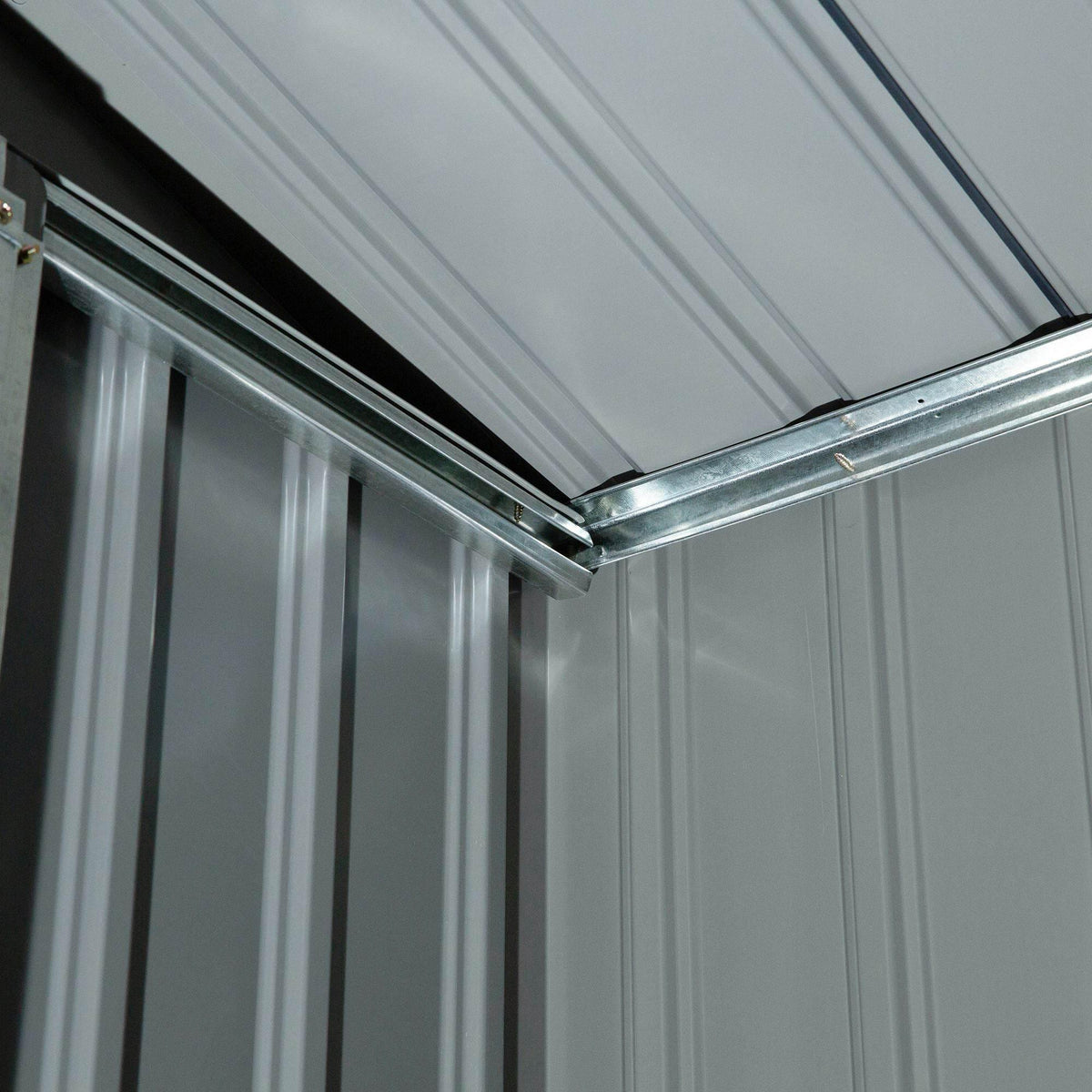 Interior corner view of light green metal garden shed with galvanized roof frame supports