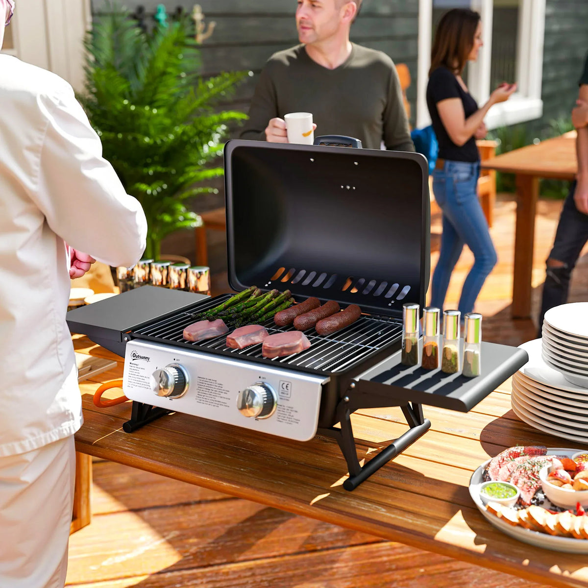 Black two-burner compact gas grill with open lid and side shelves, cooking grates