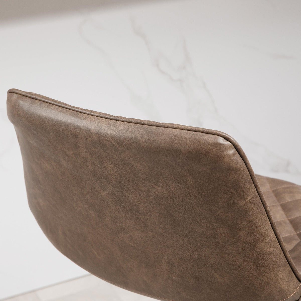 Brown PU leather bar stool side profile with padded backrest and diamond-quilted seat
