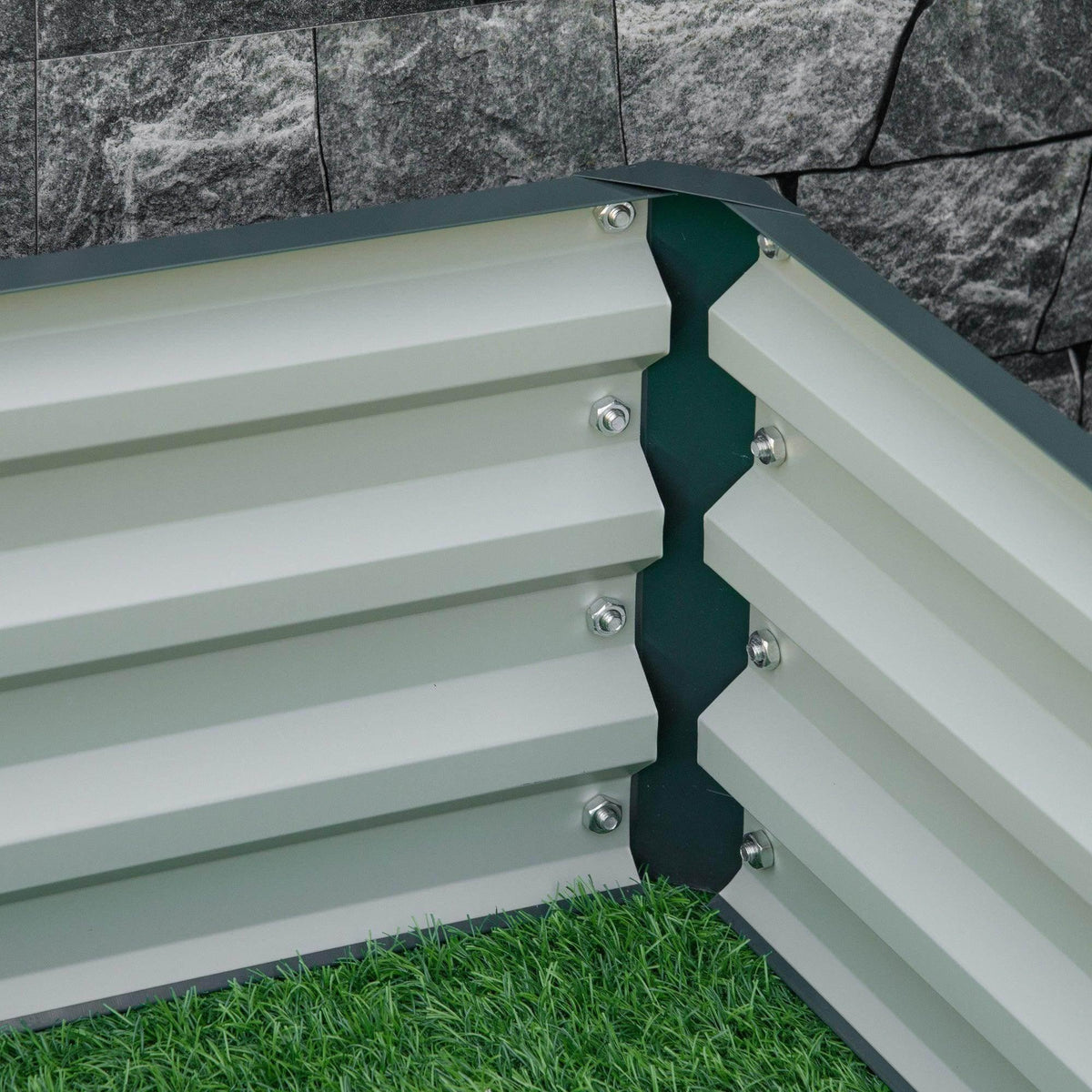 Interior corner of green metal raised garden bed with slatted panels and bolts