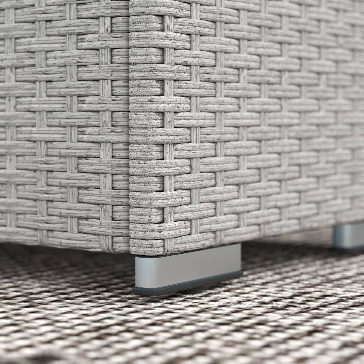 Grey rattan sofa base with protective feet on outdoor rug