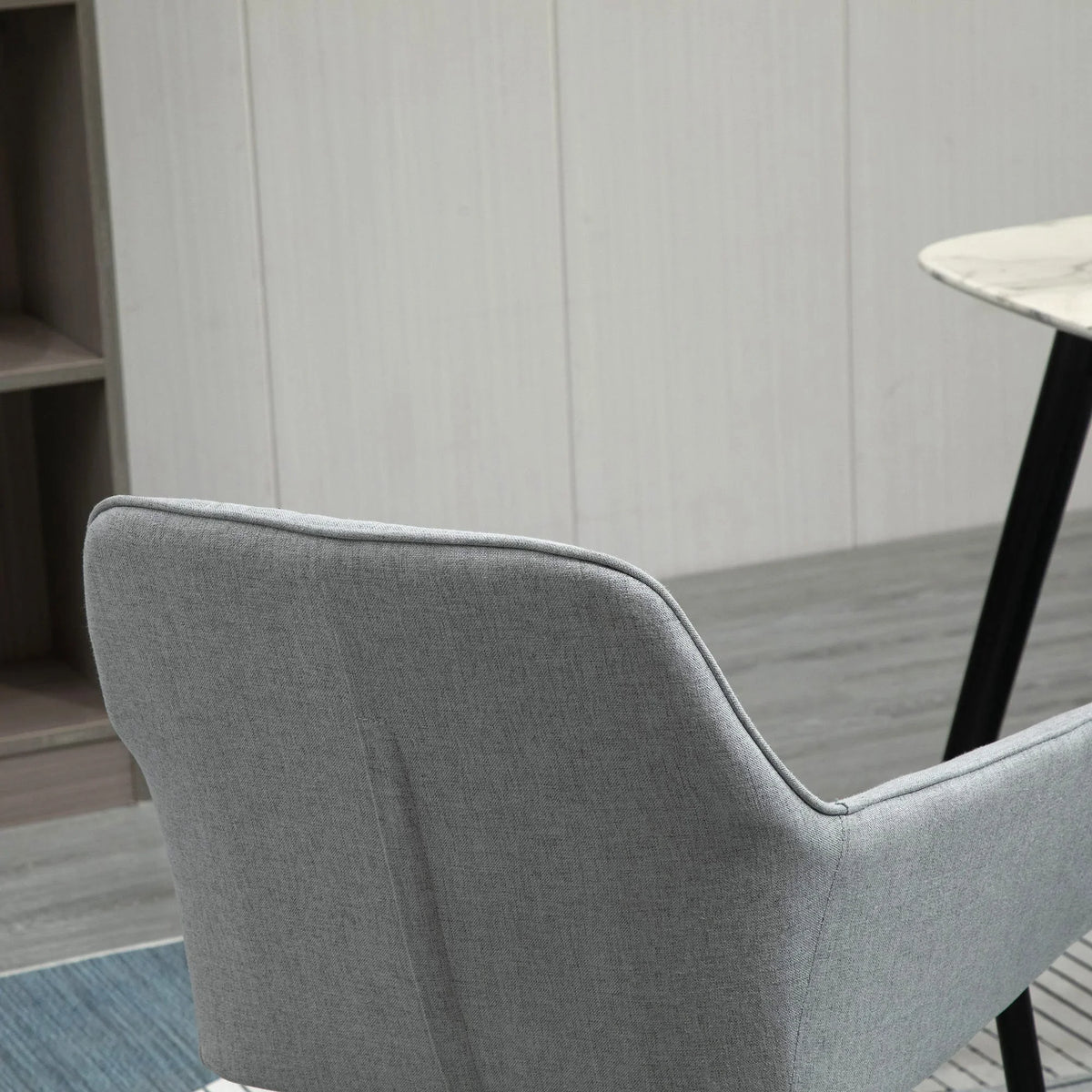 Light grey upholstered dining chair back with curved wingback and black legs