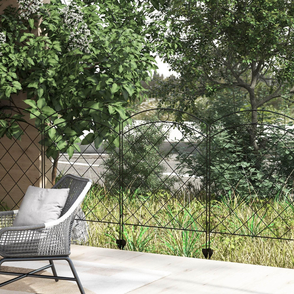 Black steel diamond-lattice garden fence panel with arched top beside outdoor seating.