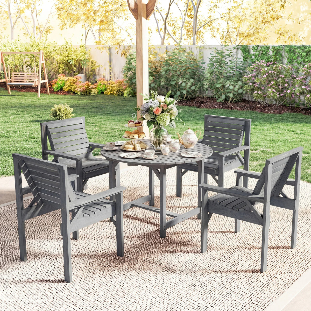 Grey outdoor dining set with round table and four slatted chairs on rug