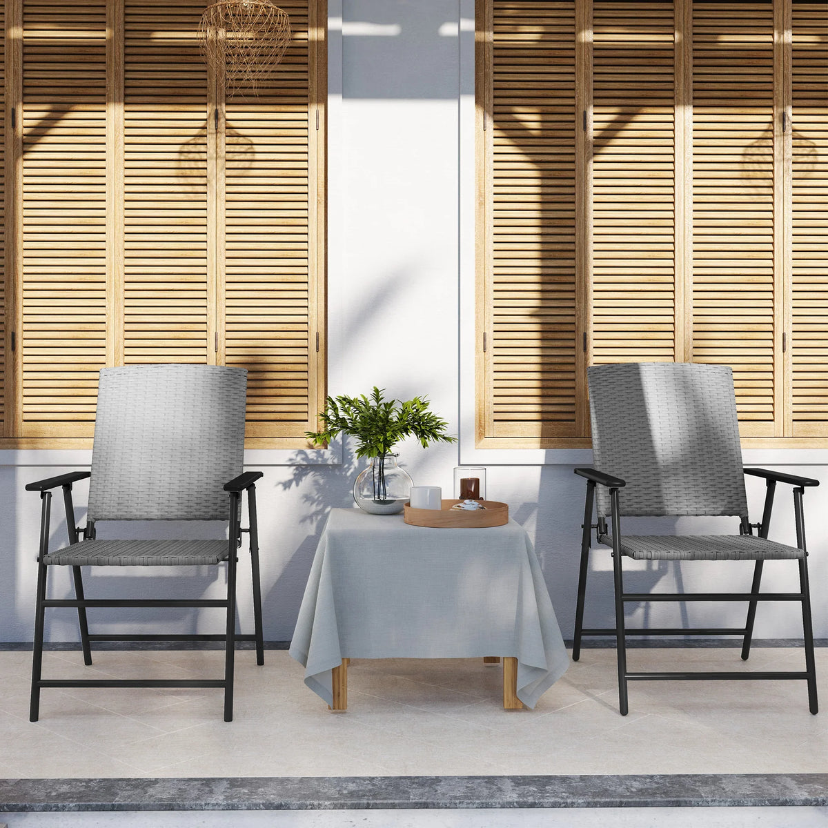 Two grey woven folding patio chairs with black steel frames on covered balcony