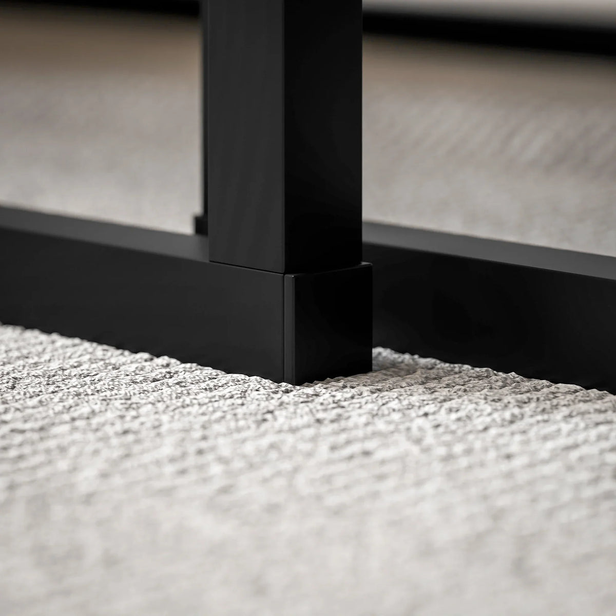 Close-up of black metal table leg under dark grey marble-effect tabletop.