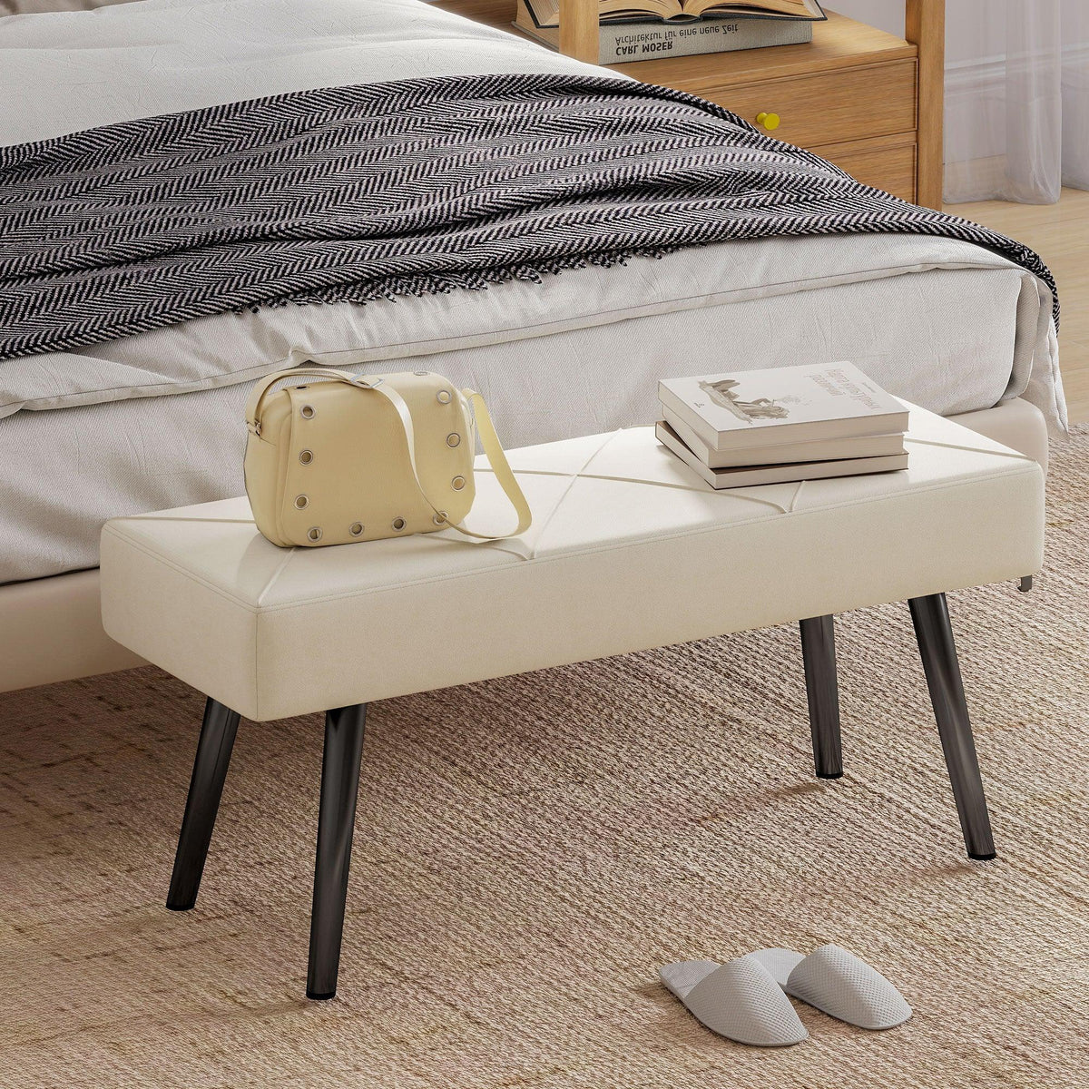 Cream upholstered bench with X-pattern stitching and black steel legs
