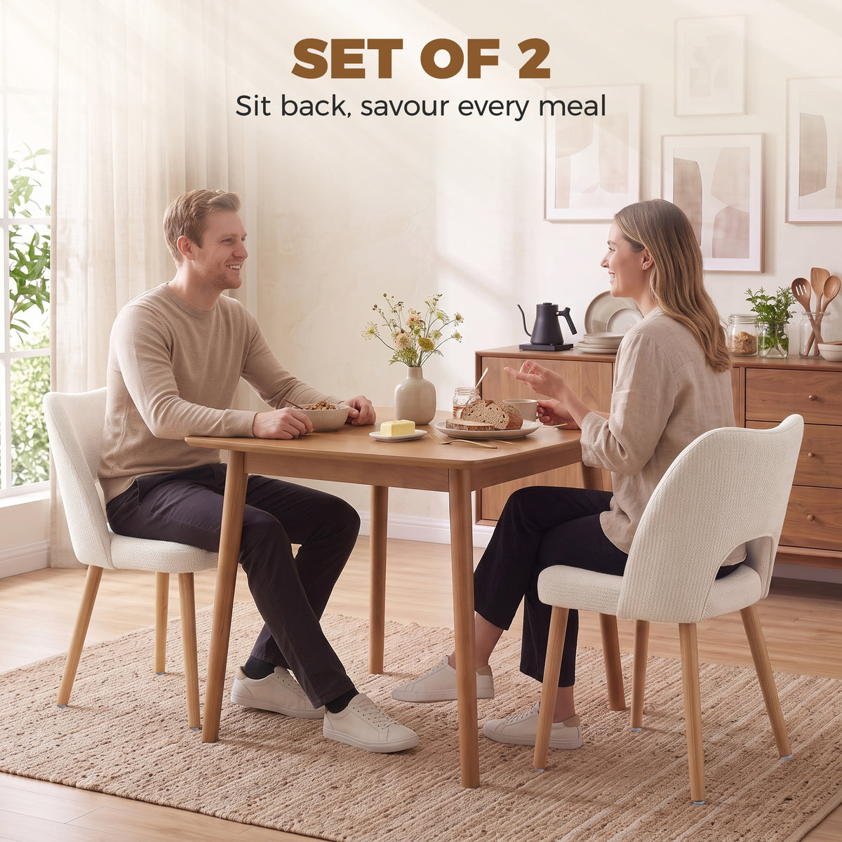 Two beige upholstered dining chairs with curved backs and light wood legs around a table.