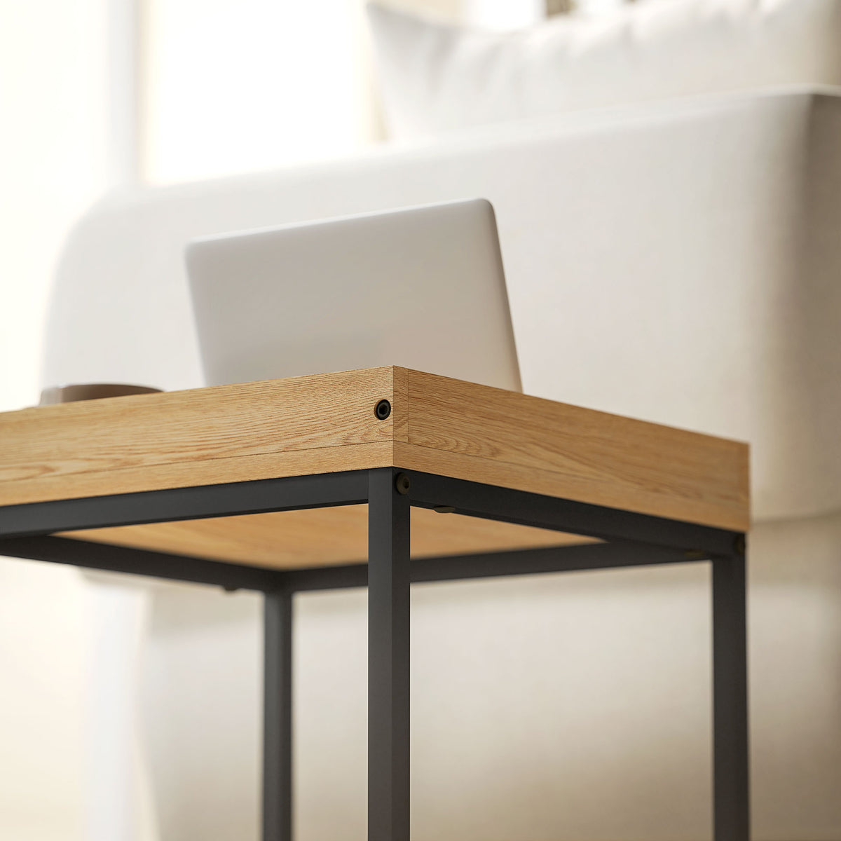 Wood-look tabletop corner with black metal legs and round screw detail
