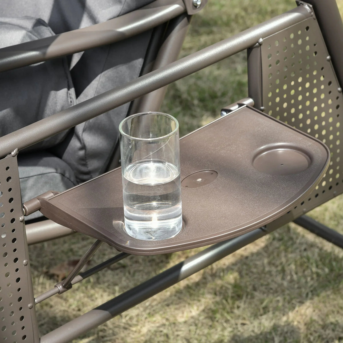 Perforated side cup tray on brown steel frame next to dark grey swing cushions