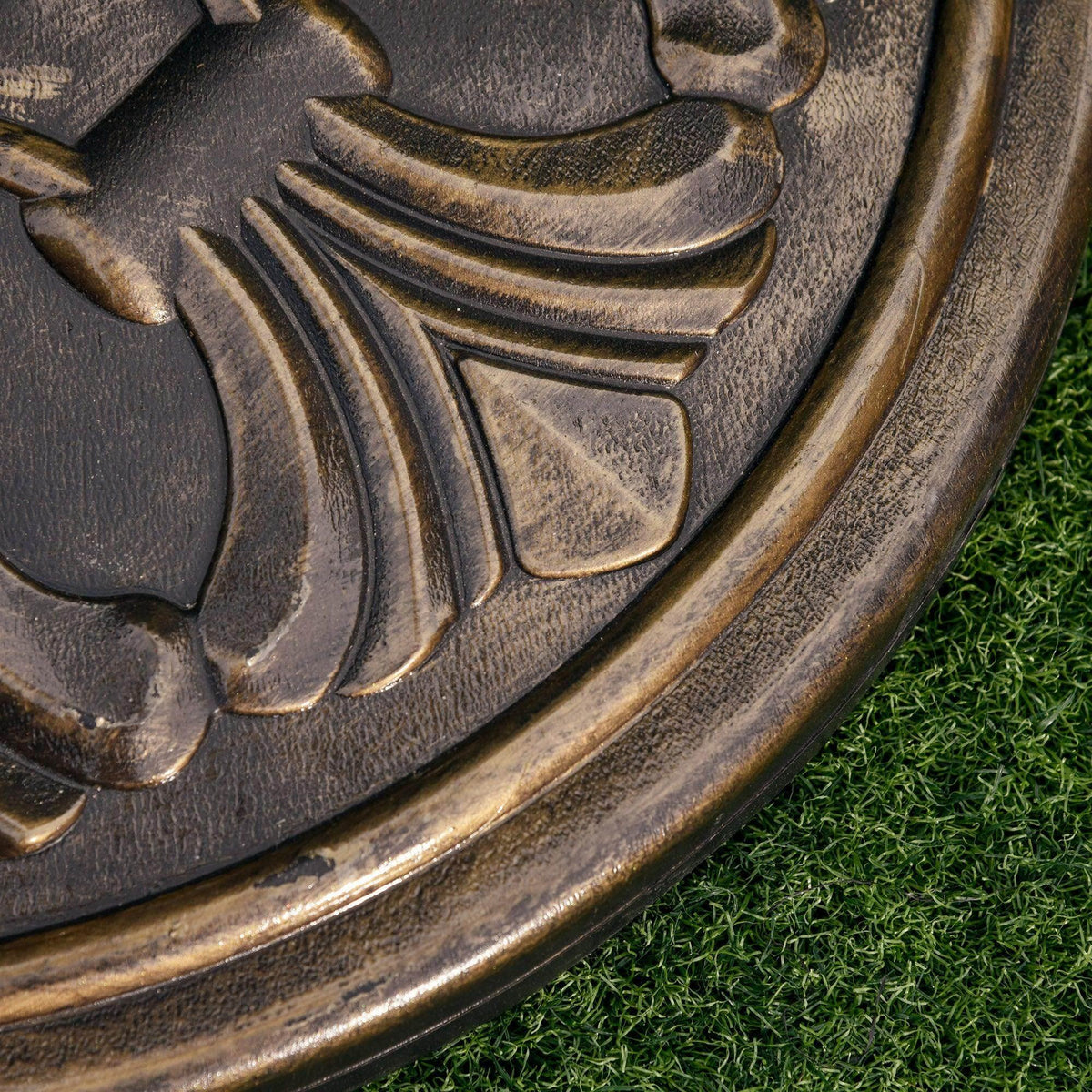 Bronze umbrella base close-up of embossed floral carving and weathered finish