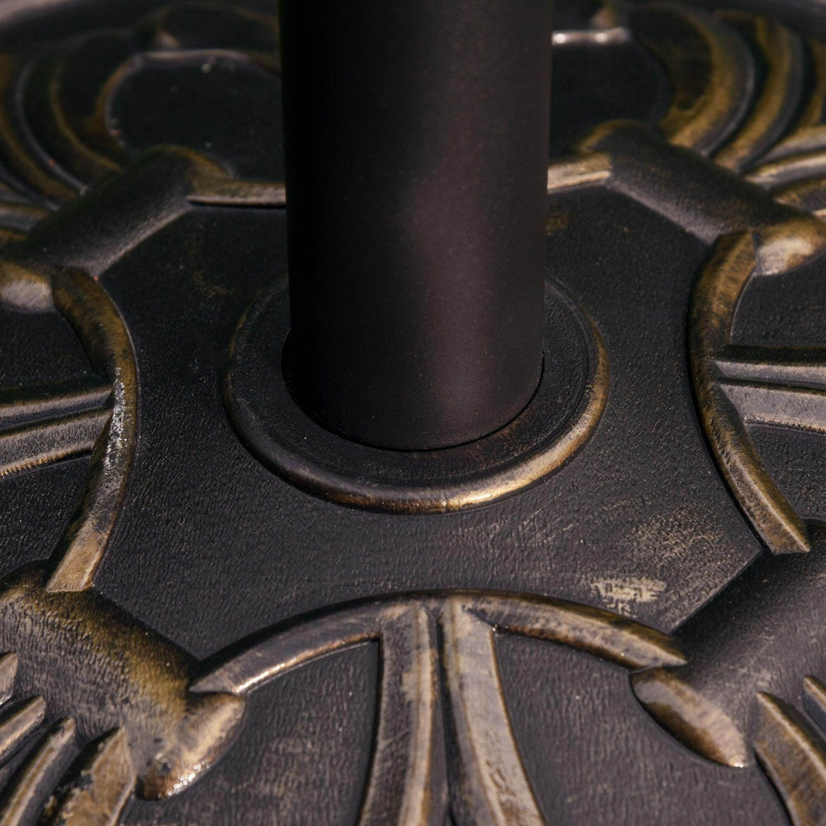 Bronze umbrella base close-up showing pole collar and decorative starburst carving