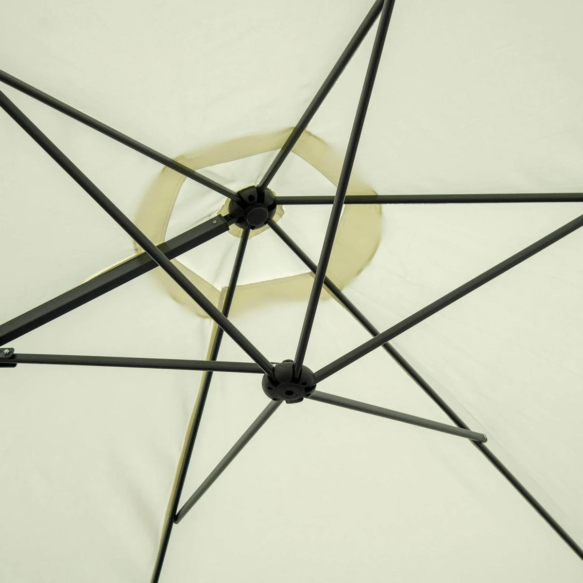 Beige cantilever umbrella canopy close-up with black ribs and central hub