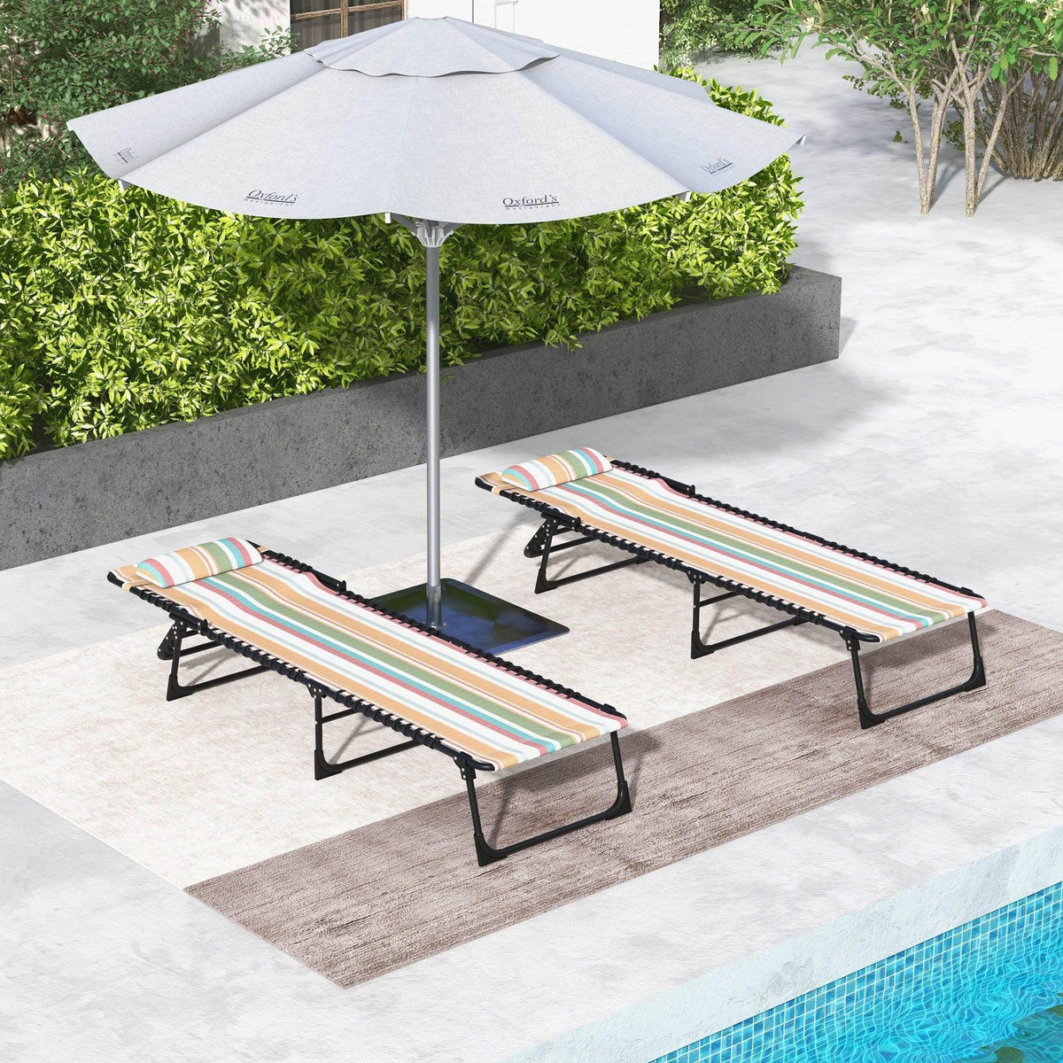 2 folding sun loungers with striped multicolor fabric cushions and black frames, under a patio umbrella