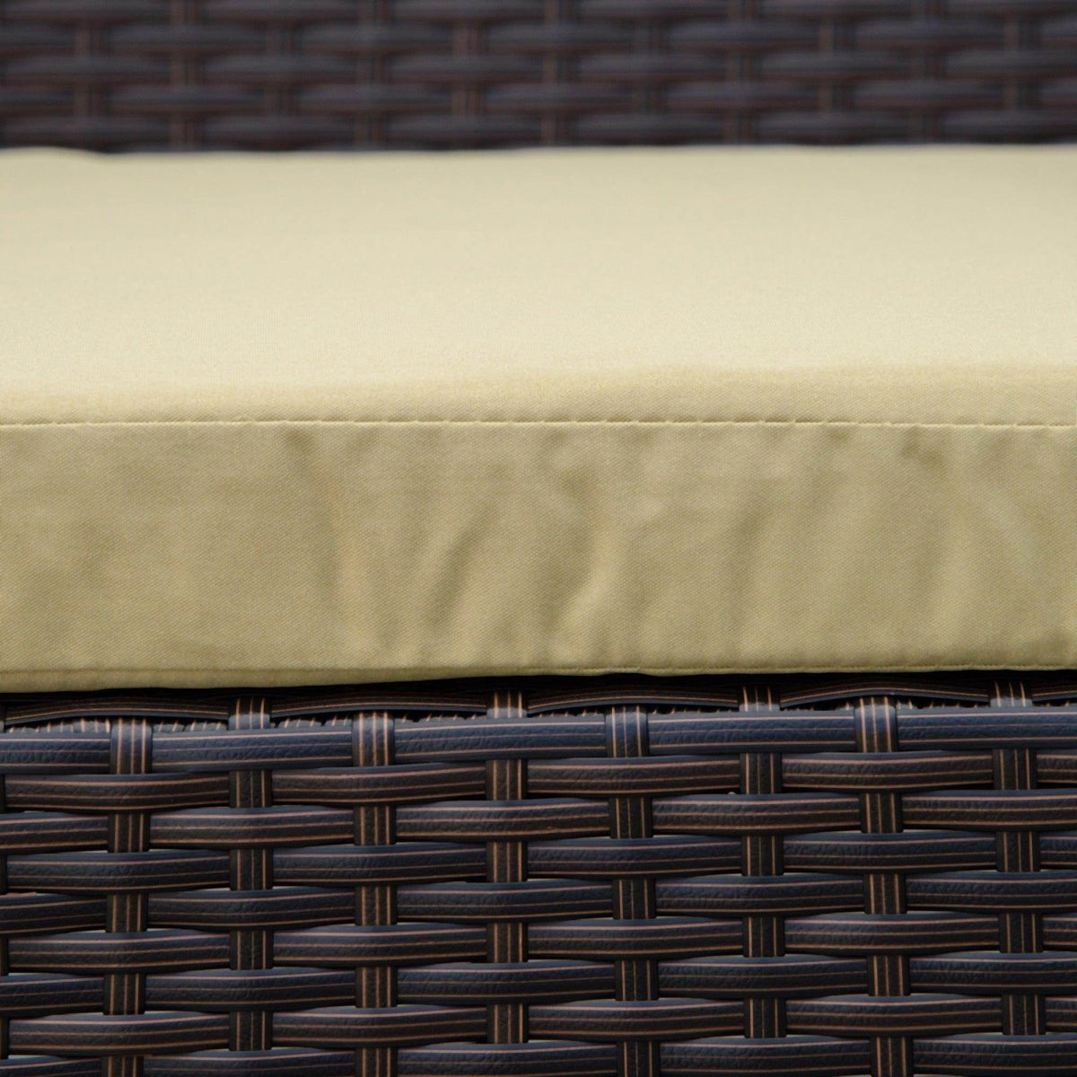 Beige seat cushion on dark woven wicker patio chair, close-up of fabric seam.