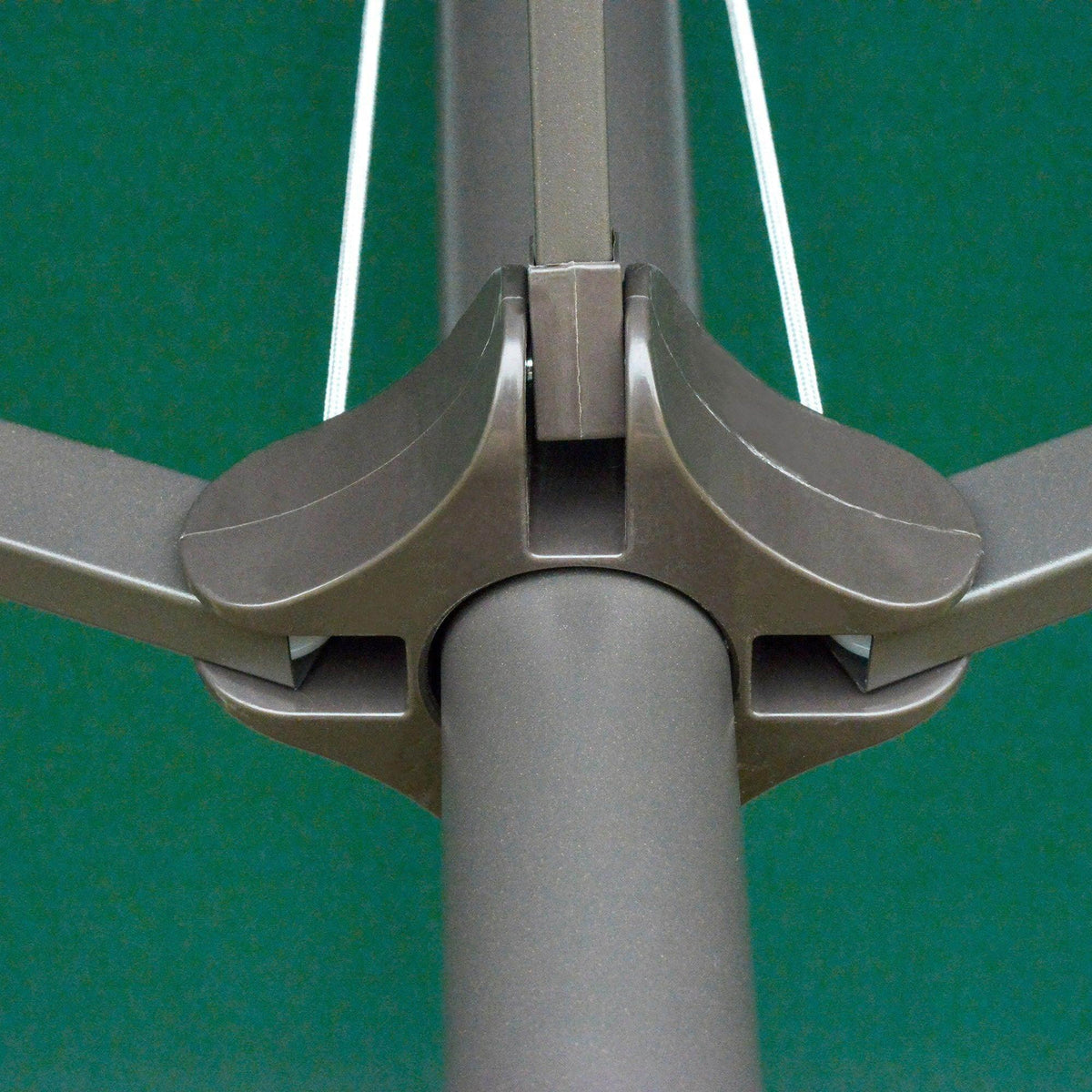 Close-up of patio umbrella crank hub and metal support arms with green canopy