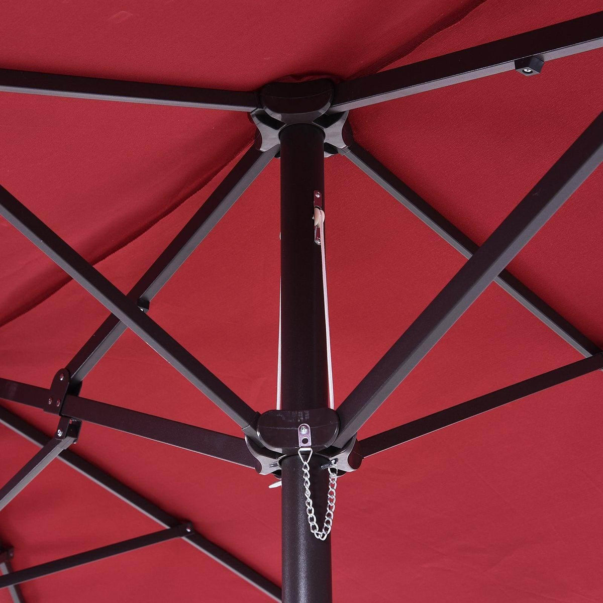 Close-up of wine red umbrella canopy ribs and locking hardware on the top pole