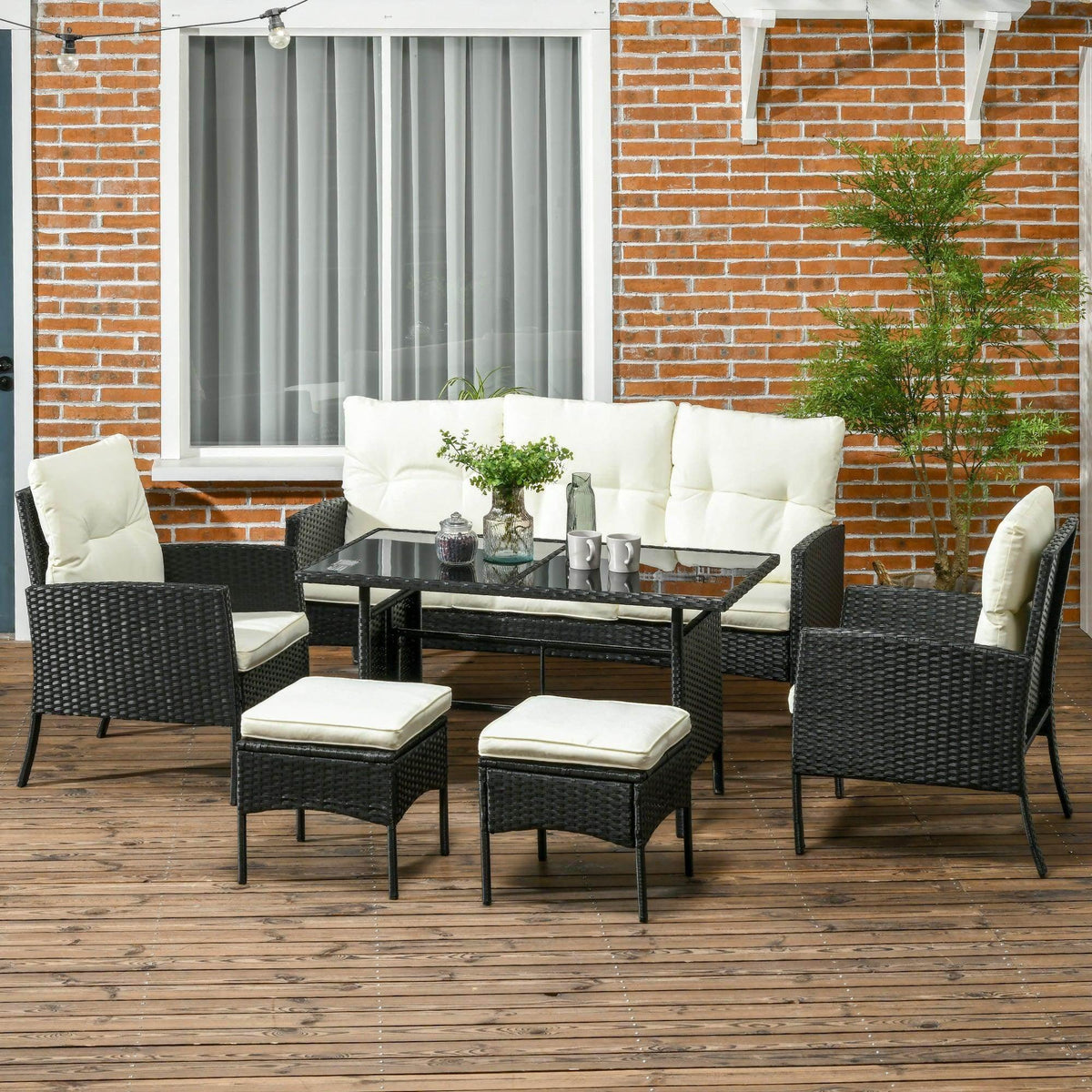 Black rattan patio seating set with glass tabletop and four cream seat cushions