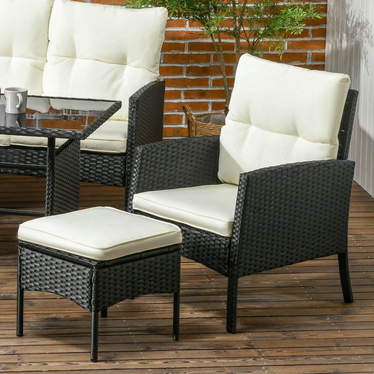 Black rattan lounge chair with cream seat and back cushions, plus matching ottoman