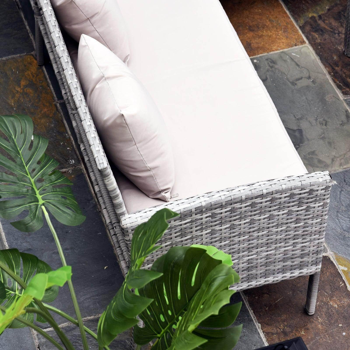 Rattan corner sofa seat with white cushions and light gray woven armrest
