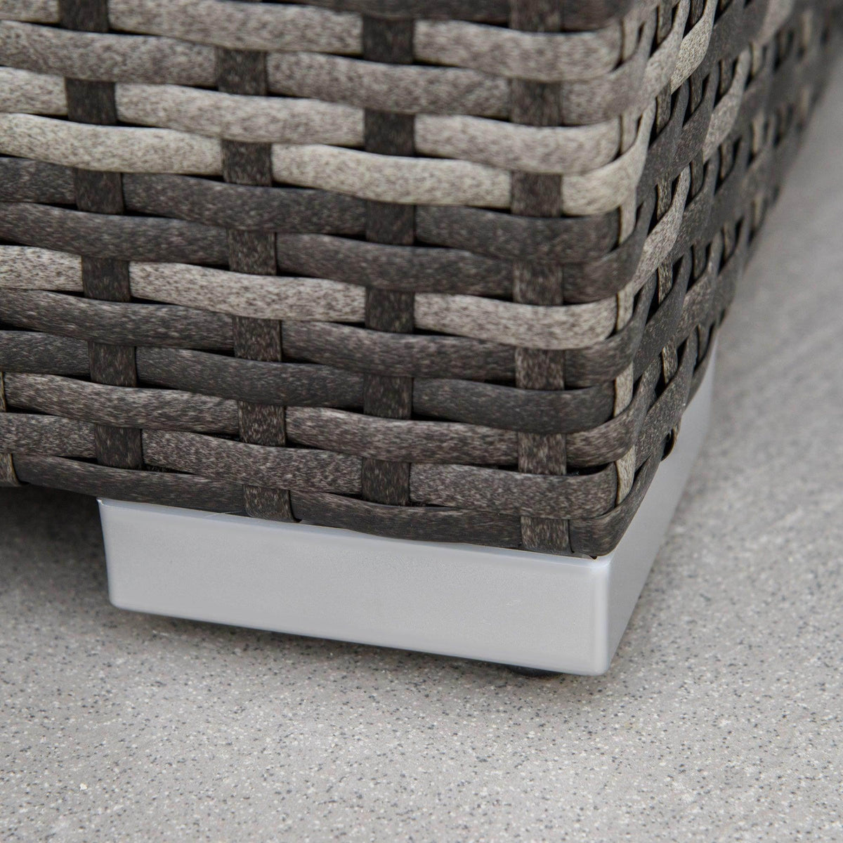 Grey rattan corner sofa base with white support feet and woven side panels