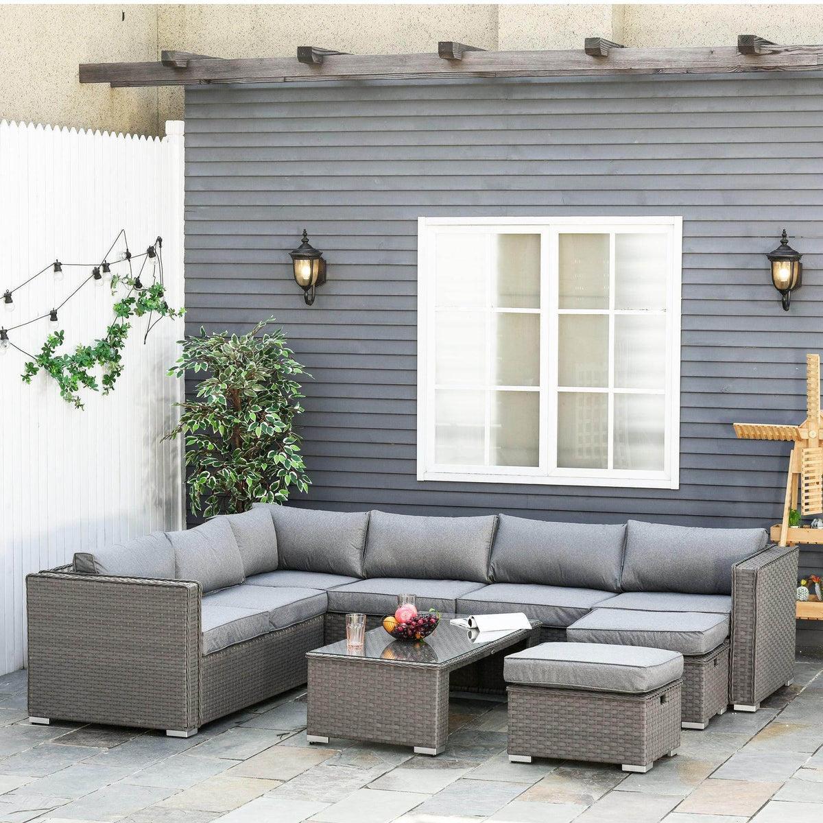 Grey outdoor sectional sofa set with seat cushions and modular ottoman seating plus coffee table.