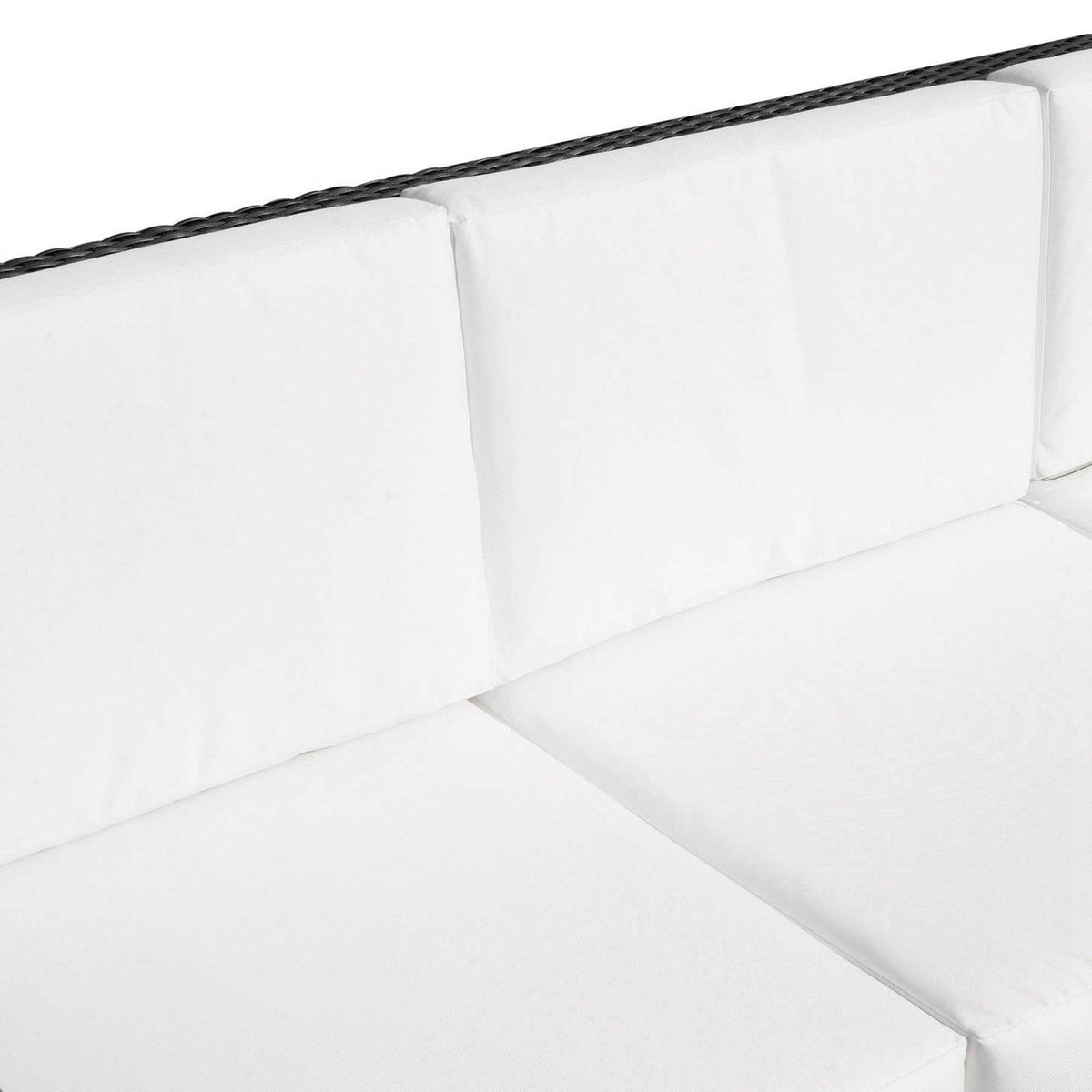 Close-up of black resin rattan sofa arm and back with white padded cushions