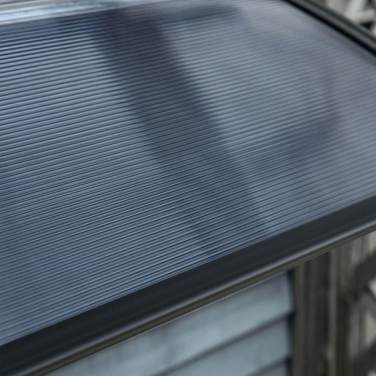 Translucent ribbed polycarbonate panel of a black door canopy awning in close-up