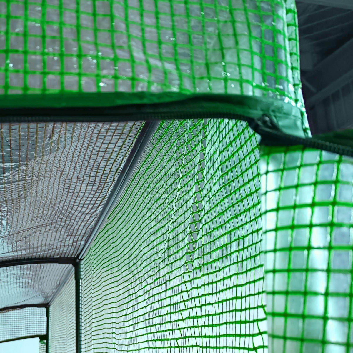 Green mesh greenhouse fabric corner close-up with curved frame and seam.
