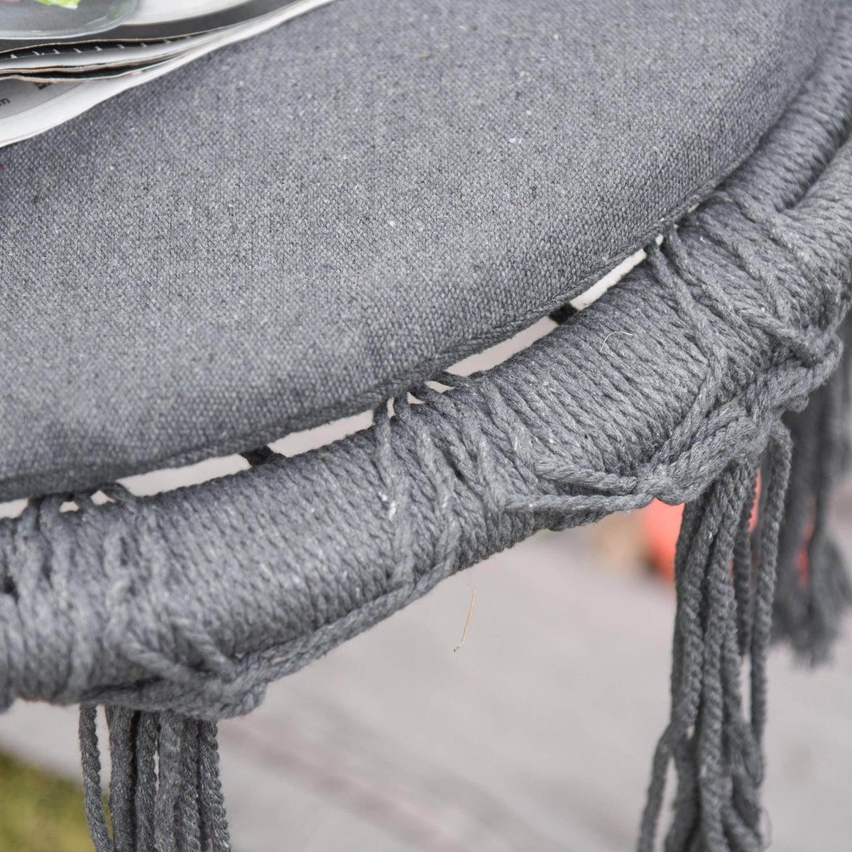 Close-up of grey macrame fringe and braided rope trim on swing chair seat