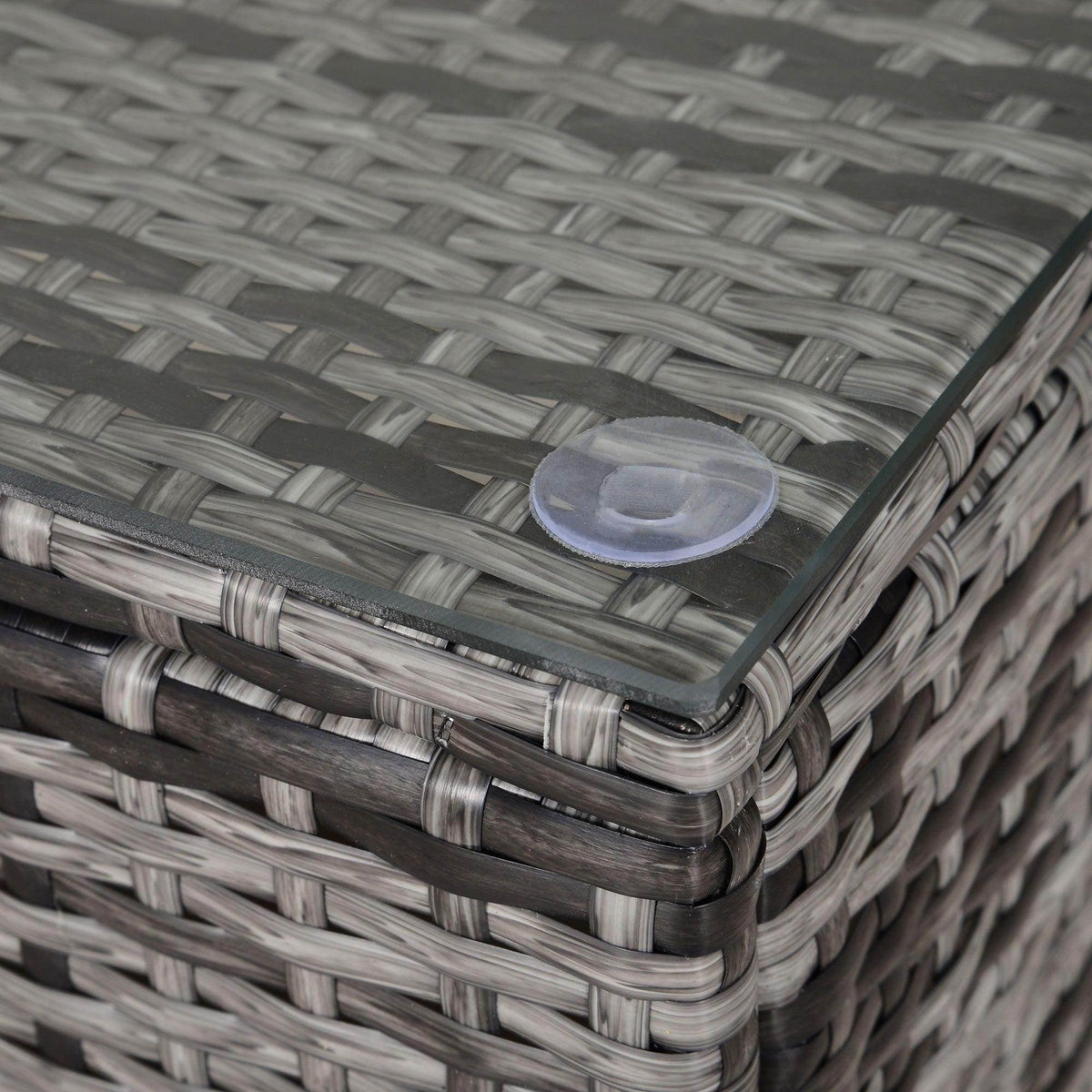Close-up of grey rattan coffee table edge with tempered glass insert.