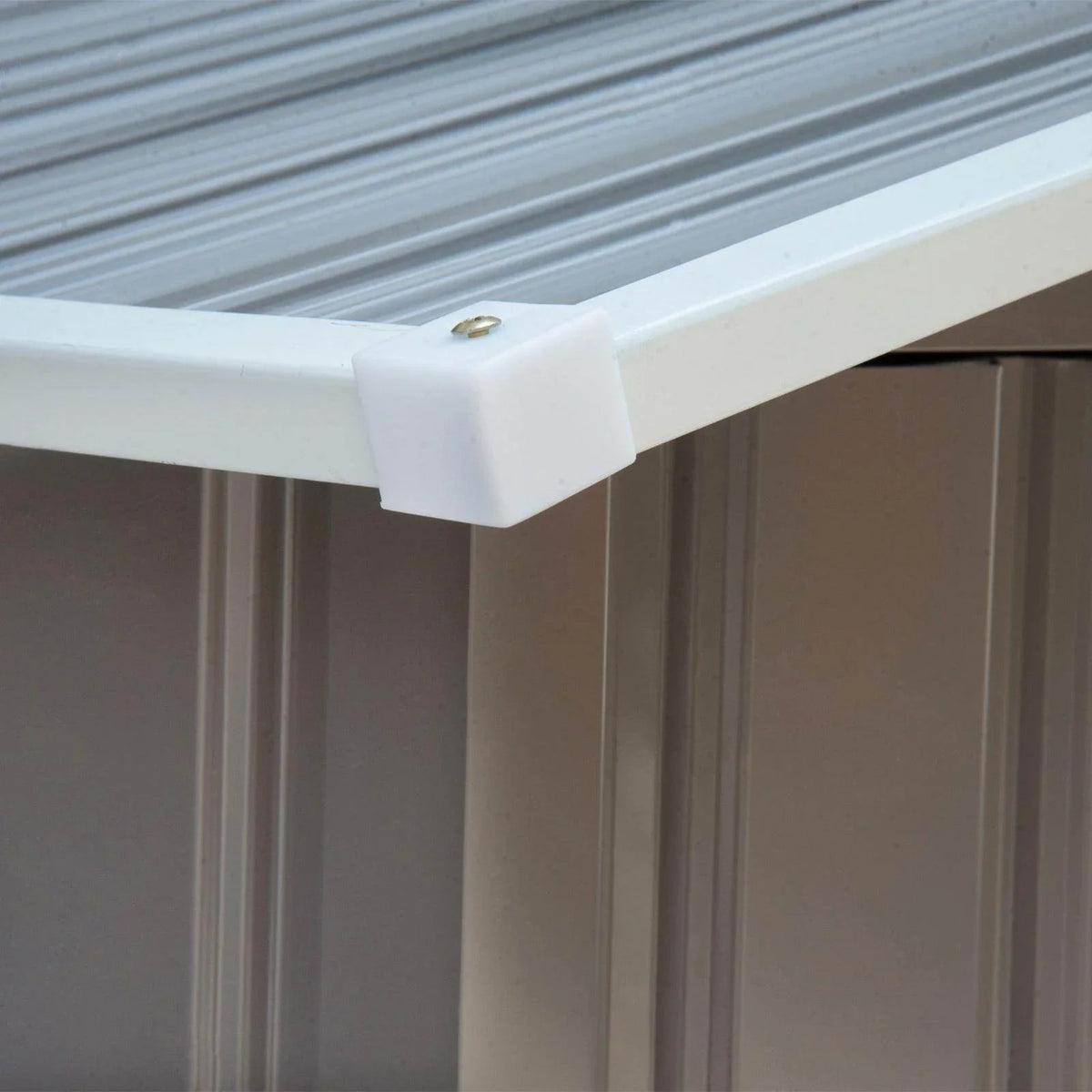 Metal garden shed roof corner detail with white trim and riveted connection