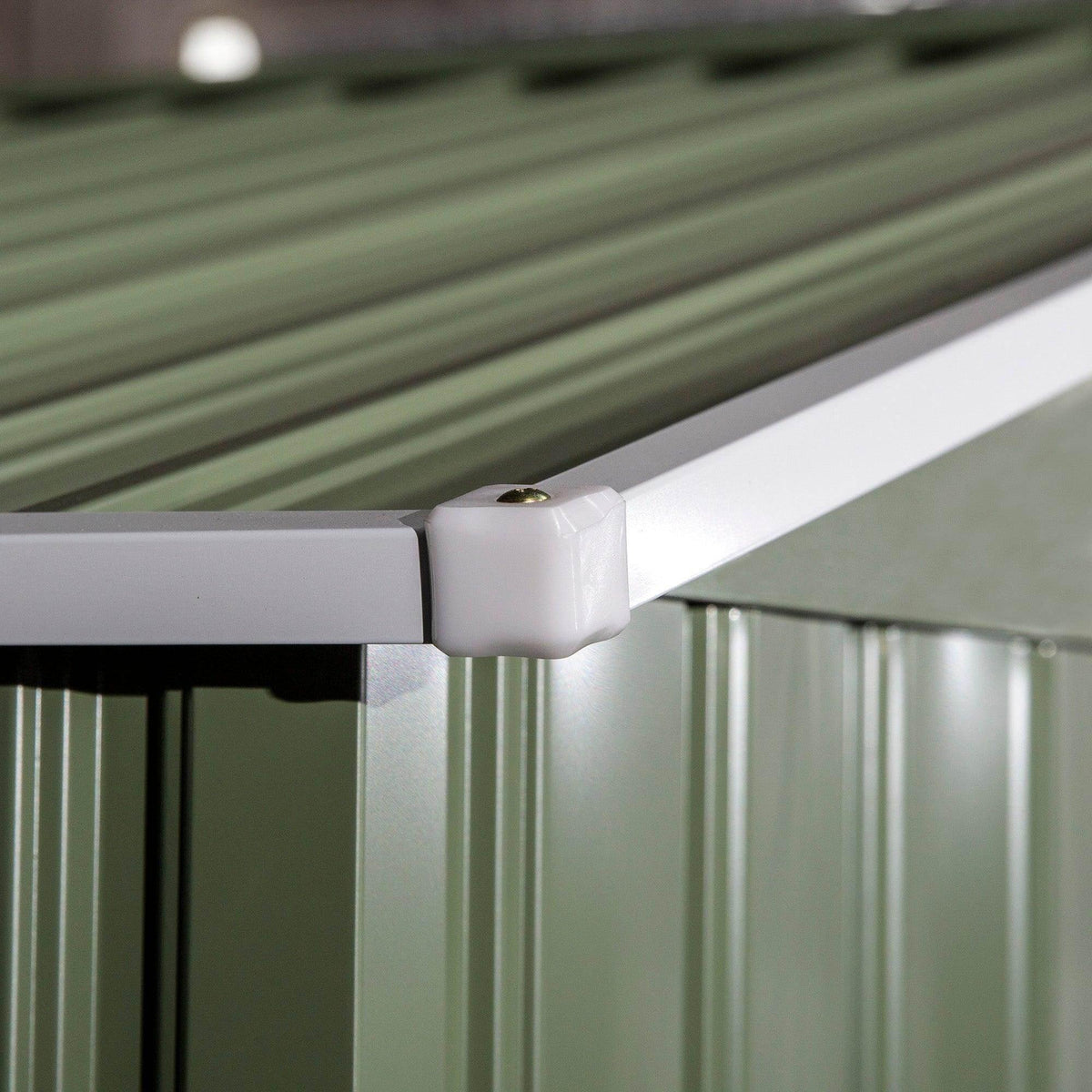 Close-up of green corrugated metal shed corner with roof edge and hardware cap