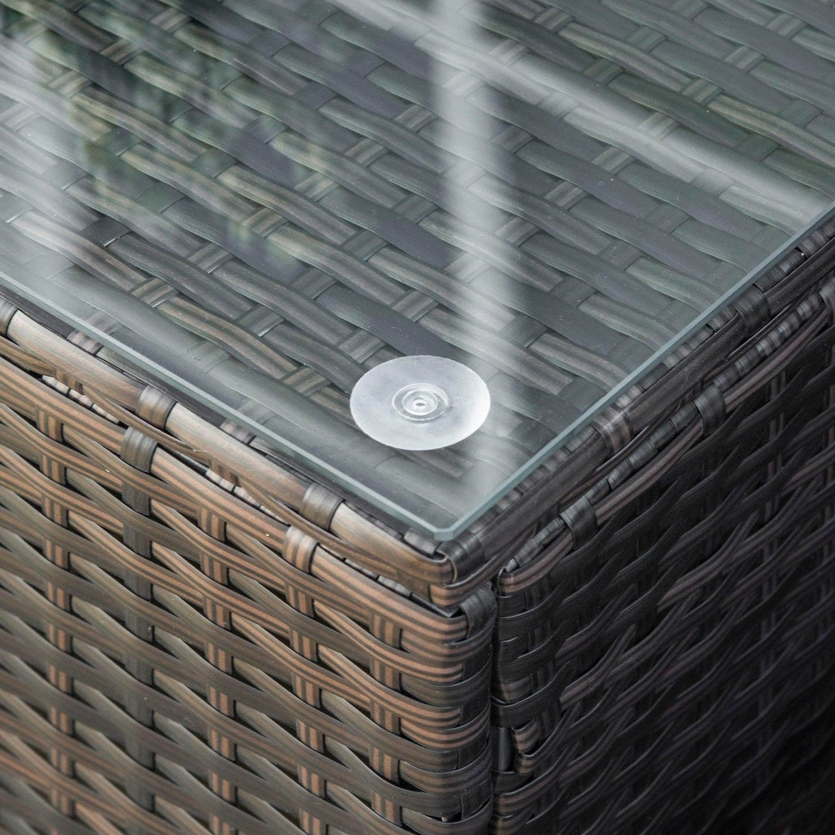 Corner close-up of mixed brown rattan coffee table with clear glass top