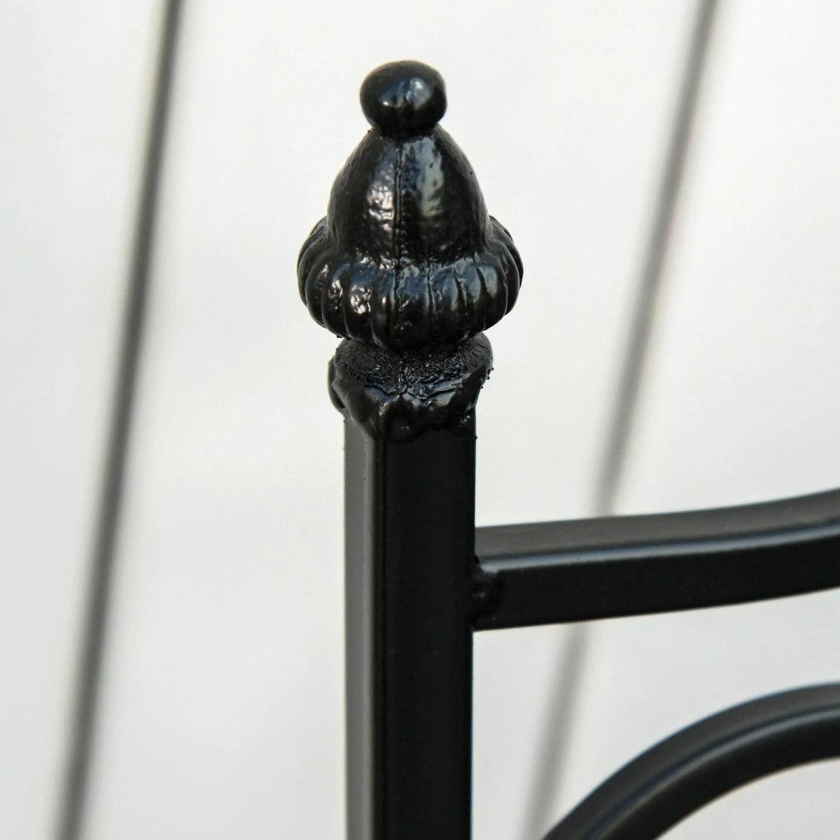 Close-up of black ornate chair frame finial on curved armrest
