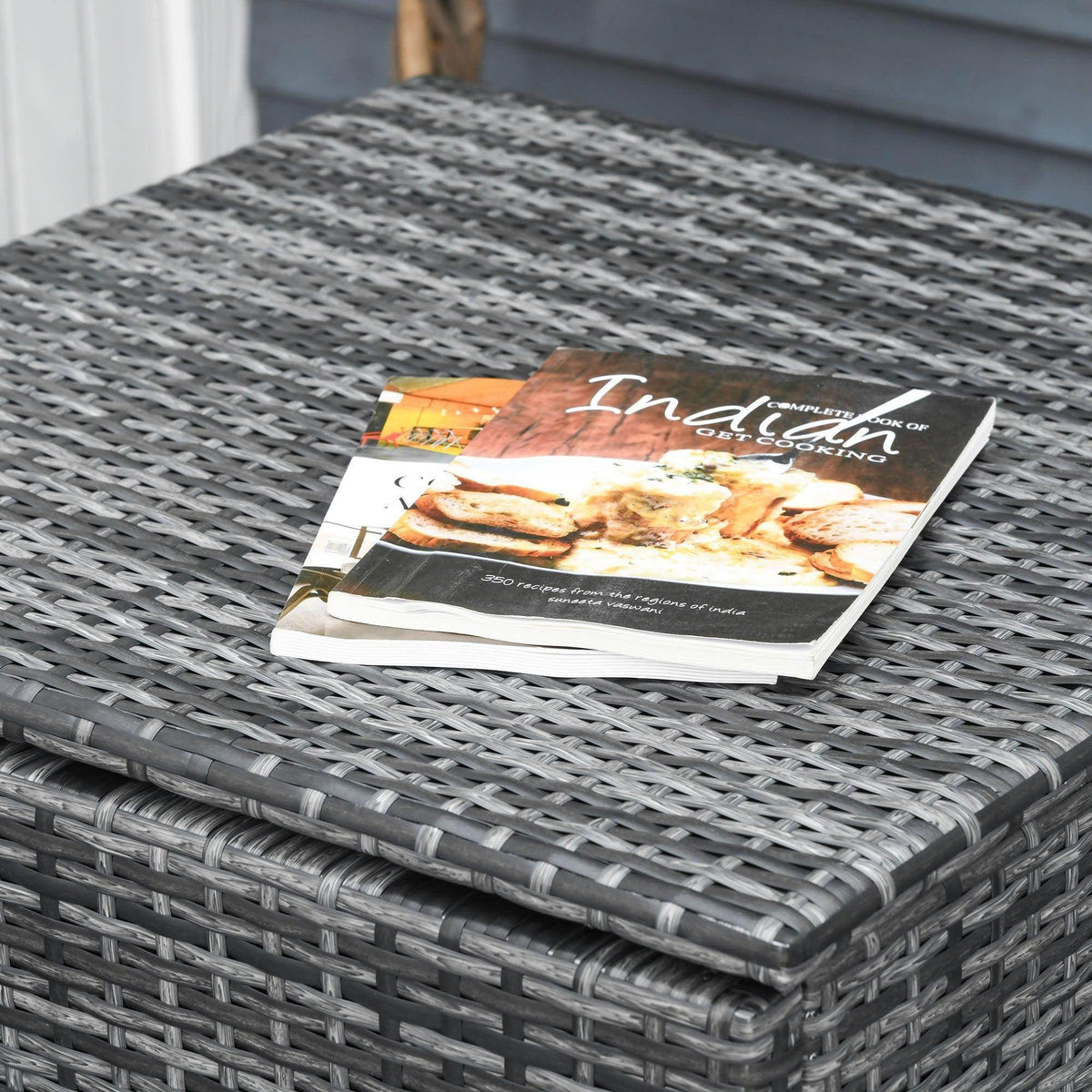 Grey wicker coffee table with glass top and cushion cover on tabletop