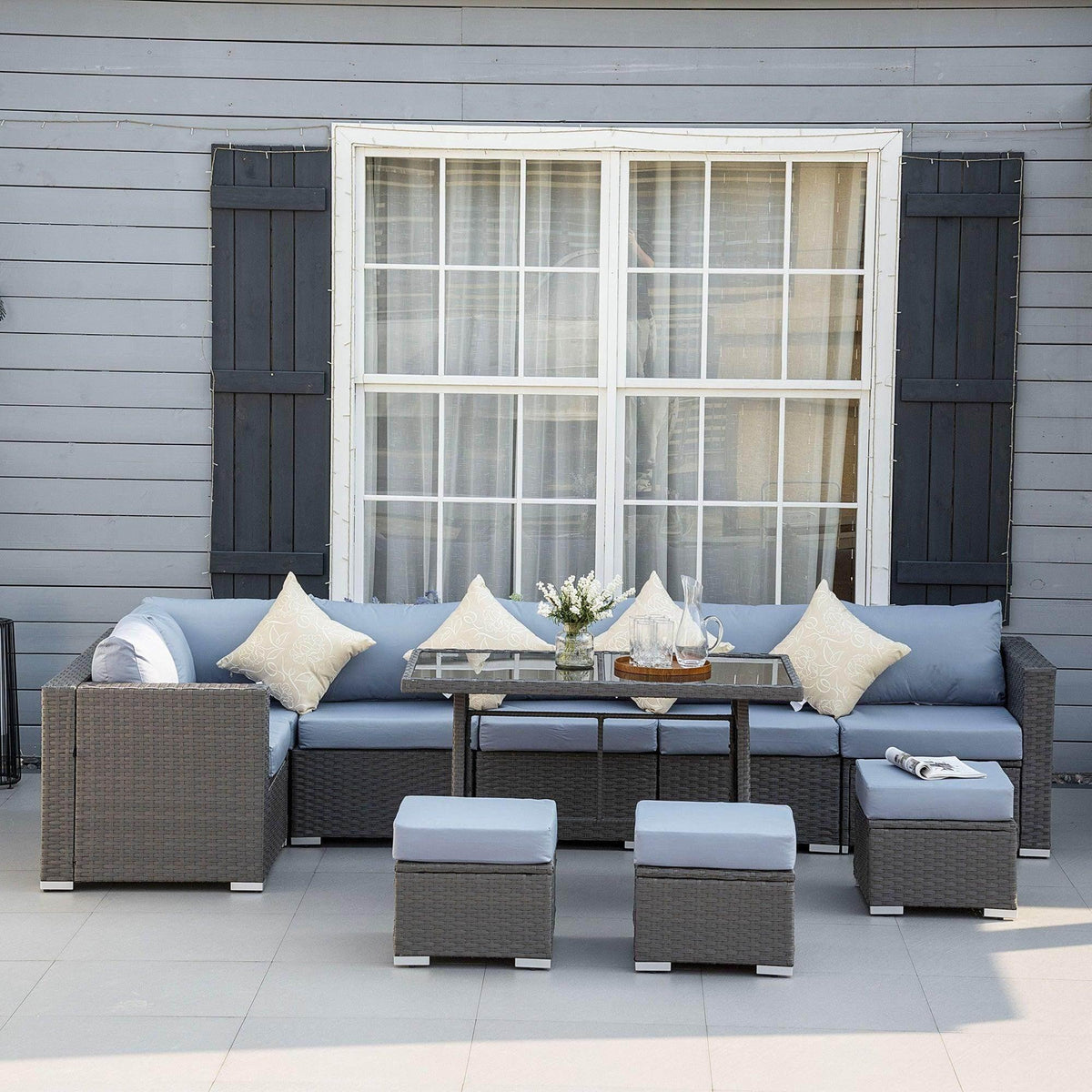 Outdoor rattan corner dining sofa set with dark gray cushions, table, and ottomans