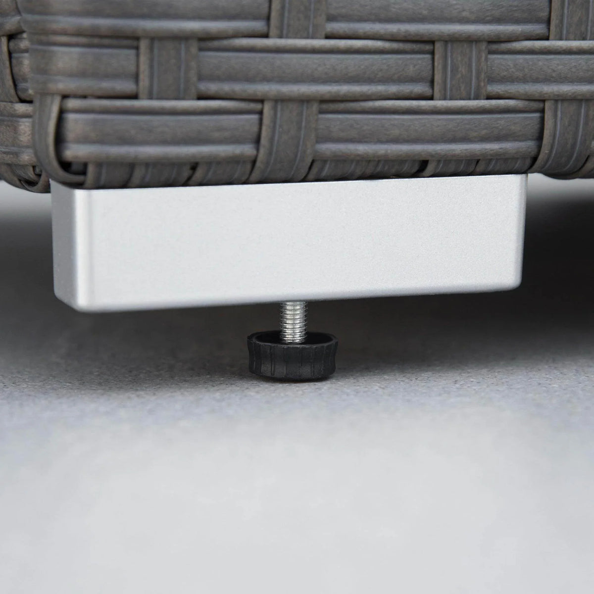 Woven rattan furniture base with adjustable leveling foot under cushion seating