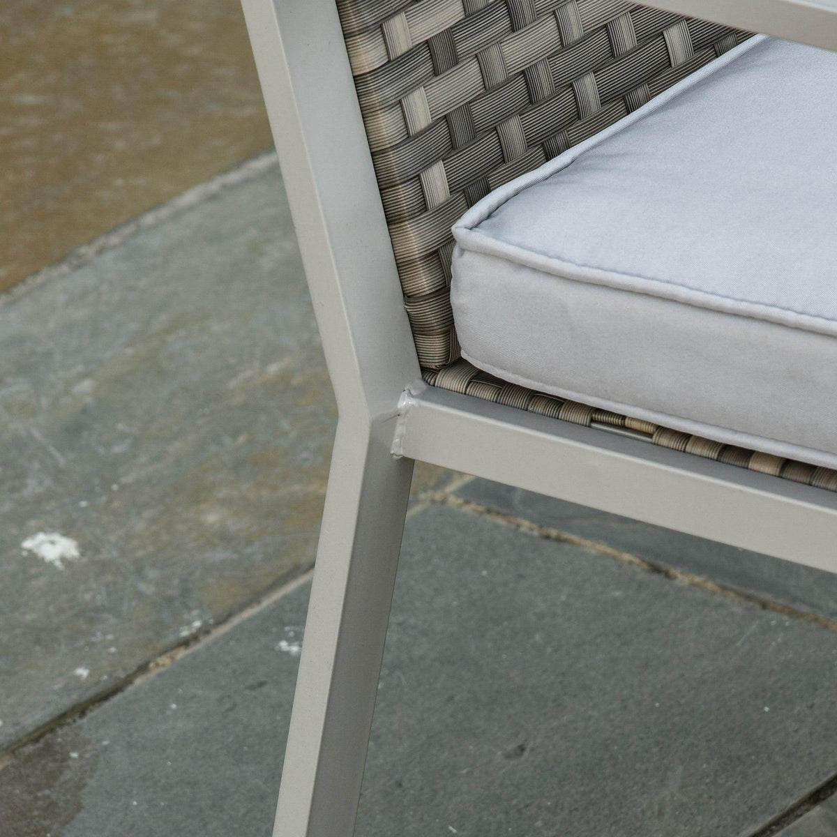 Close-up of resin wicker seat and light gray cushion on a gray metal chair frame