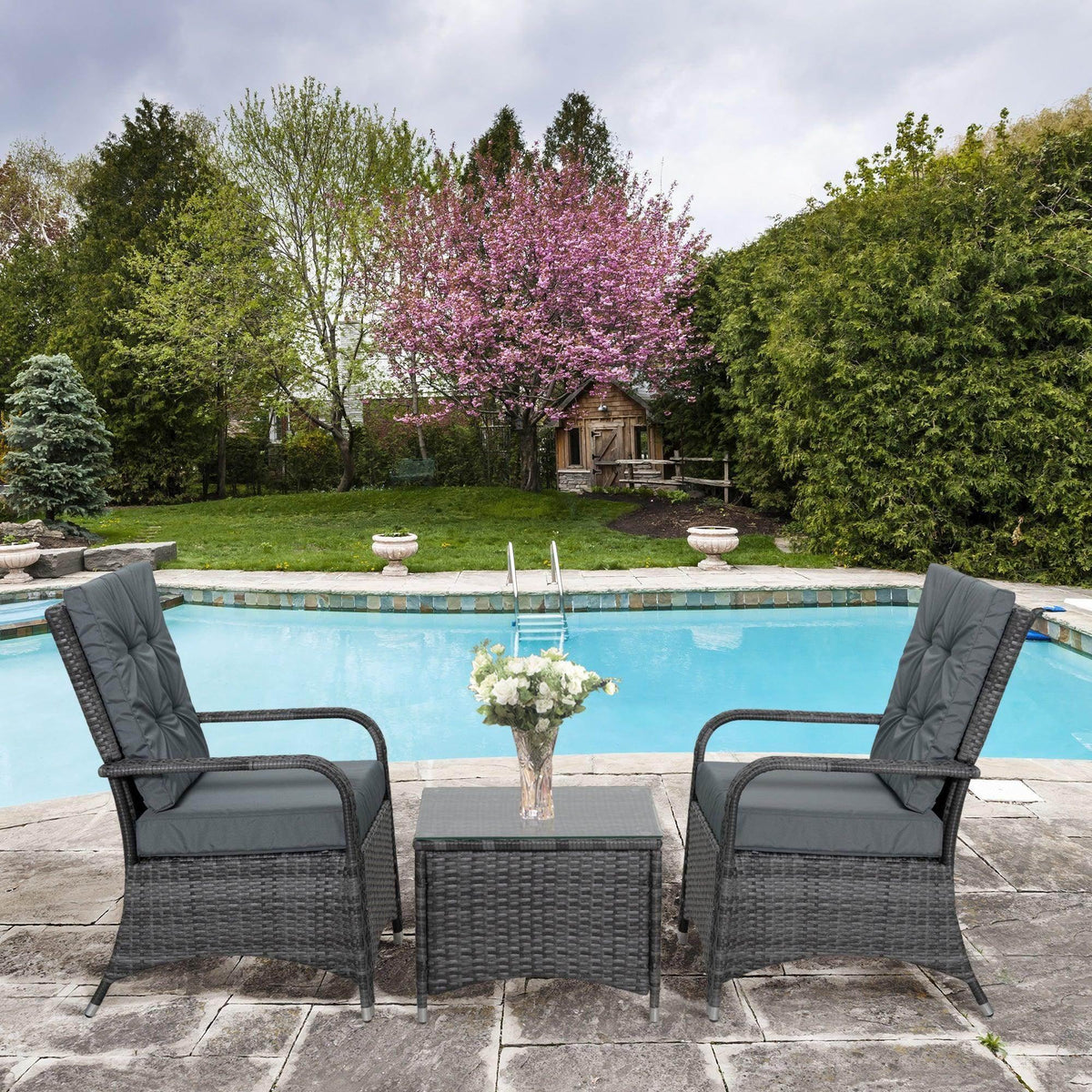 Grey rattan garden sofa set with two armchairs, glass-top table, and dark grey cushions
