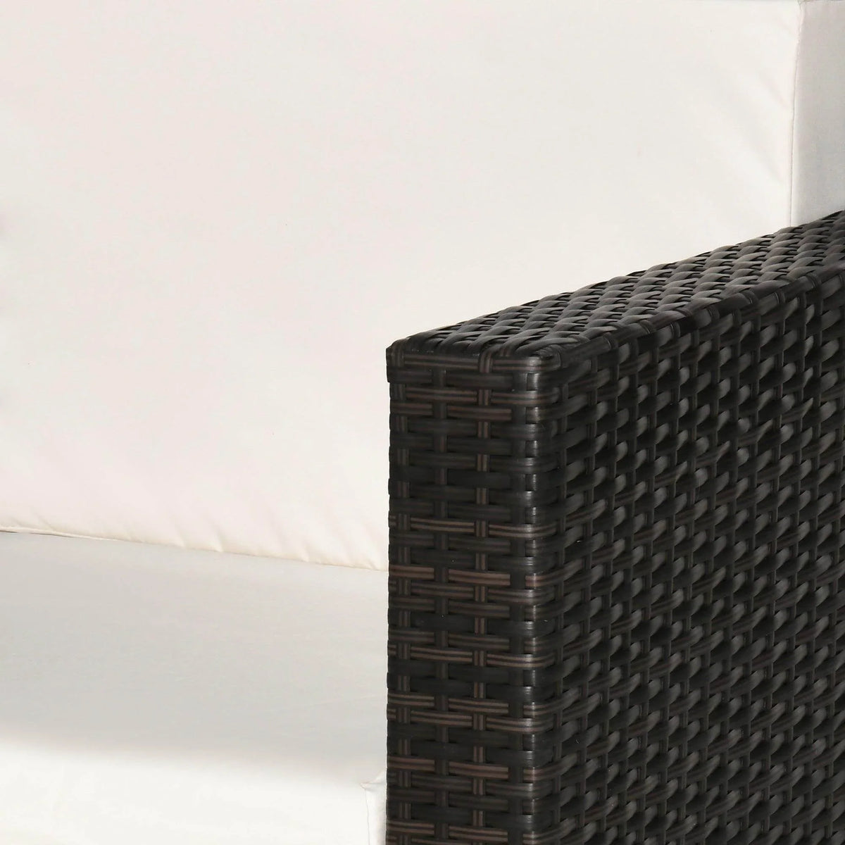 Dark woven wicker outdoor sofa arm with white cushion, ideal for patio or garden seating