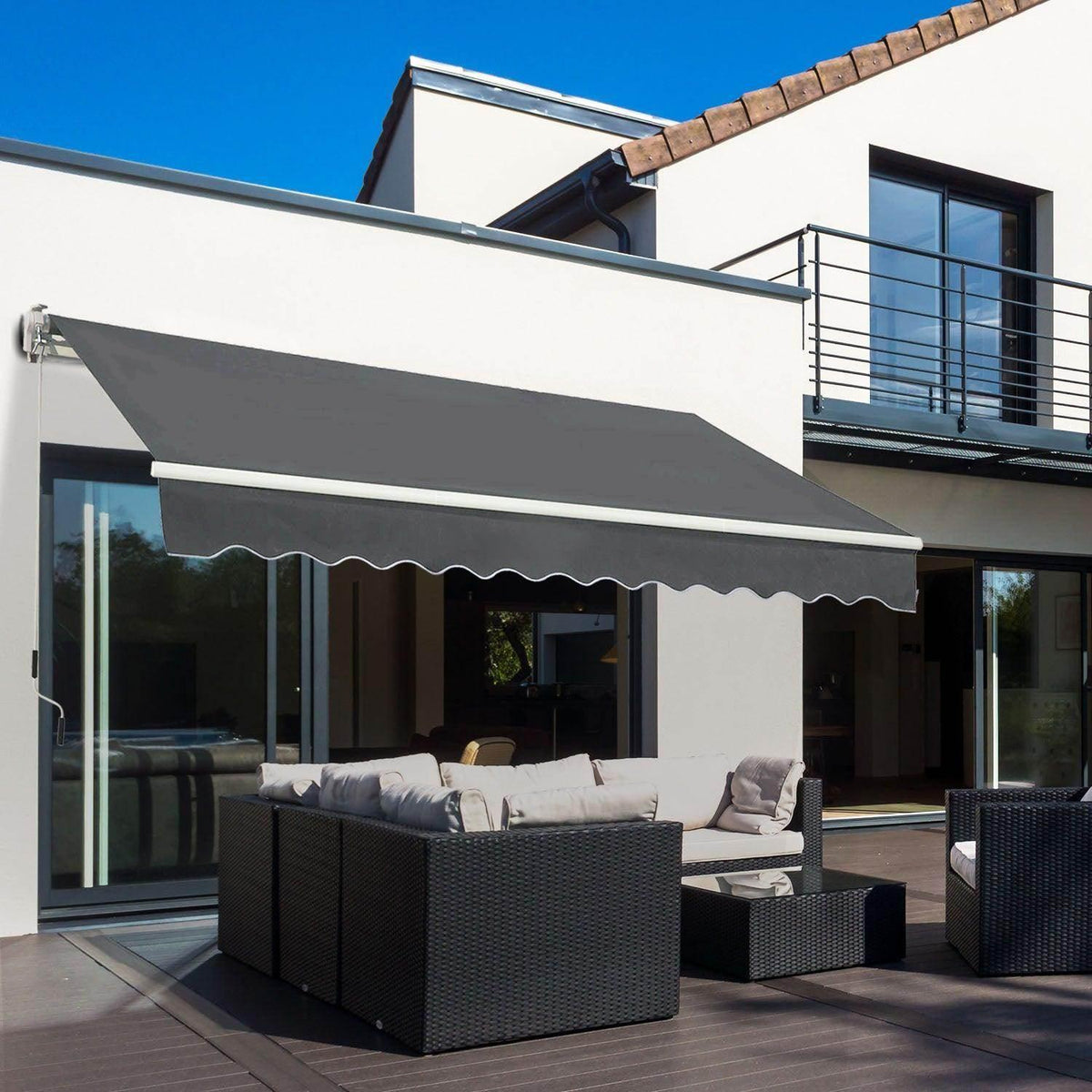 Retractable awning canopy with dark gray fabric and scalloped valance, mounted on white wall
