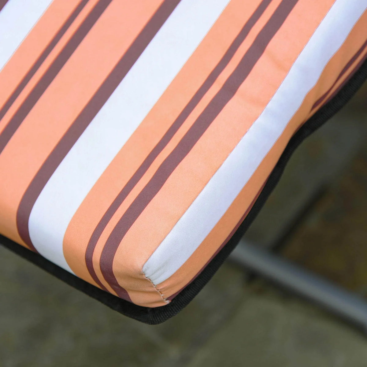 Orange, white, and brown striped outdoor cushion with black trim, perfect for garden or patio furniture.