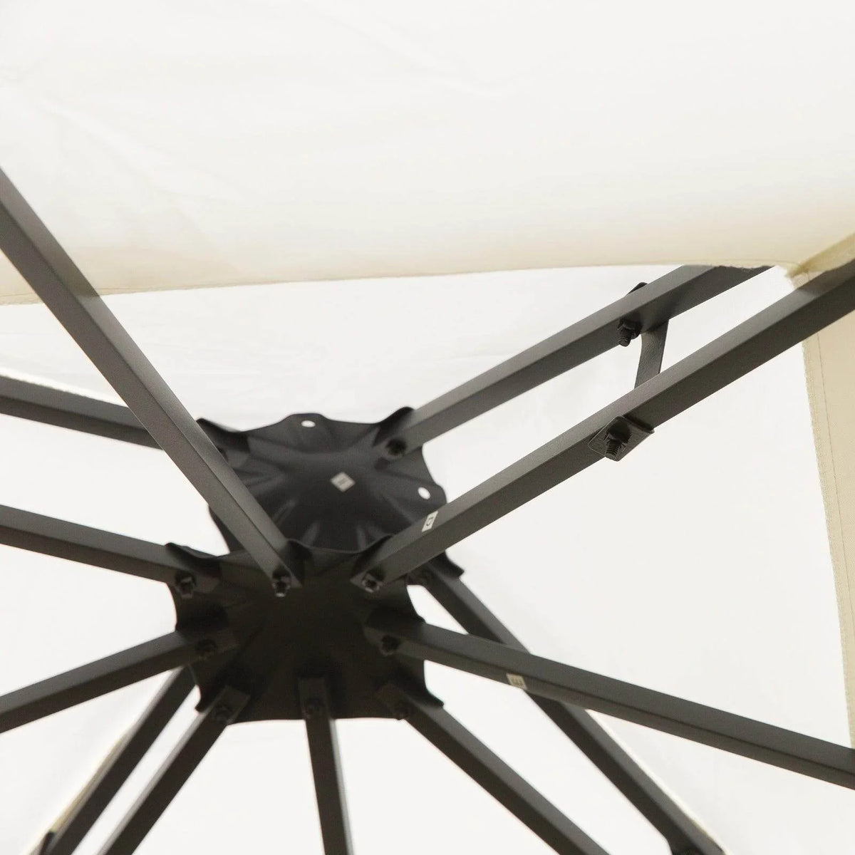 Black steel gazebo frame joint with cross support bars beneath cream canopy